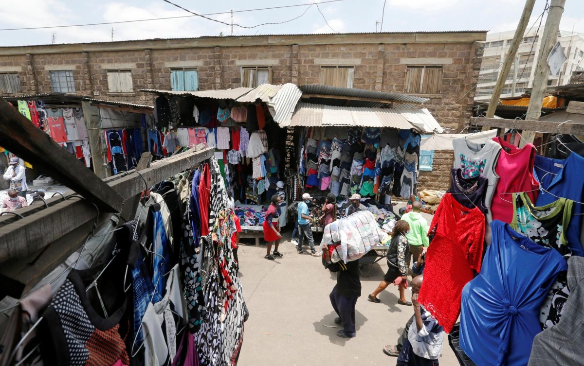 A worker carries a bale of imported second-hand clothes past displayed apparel at the Gikomba market in Nairobi, Kenya September 18, 2020. REUTERS/Thomas Mukoya